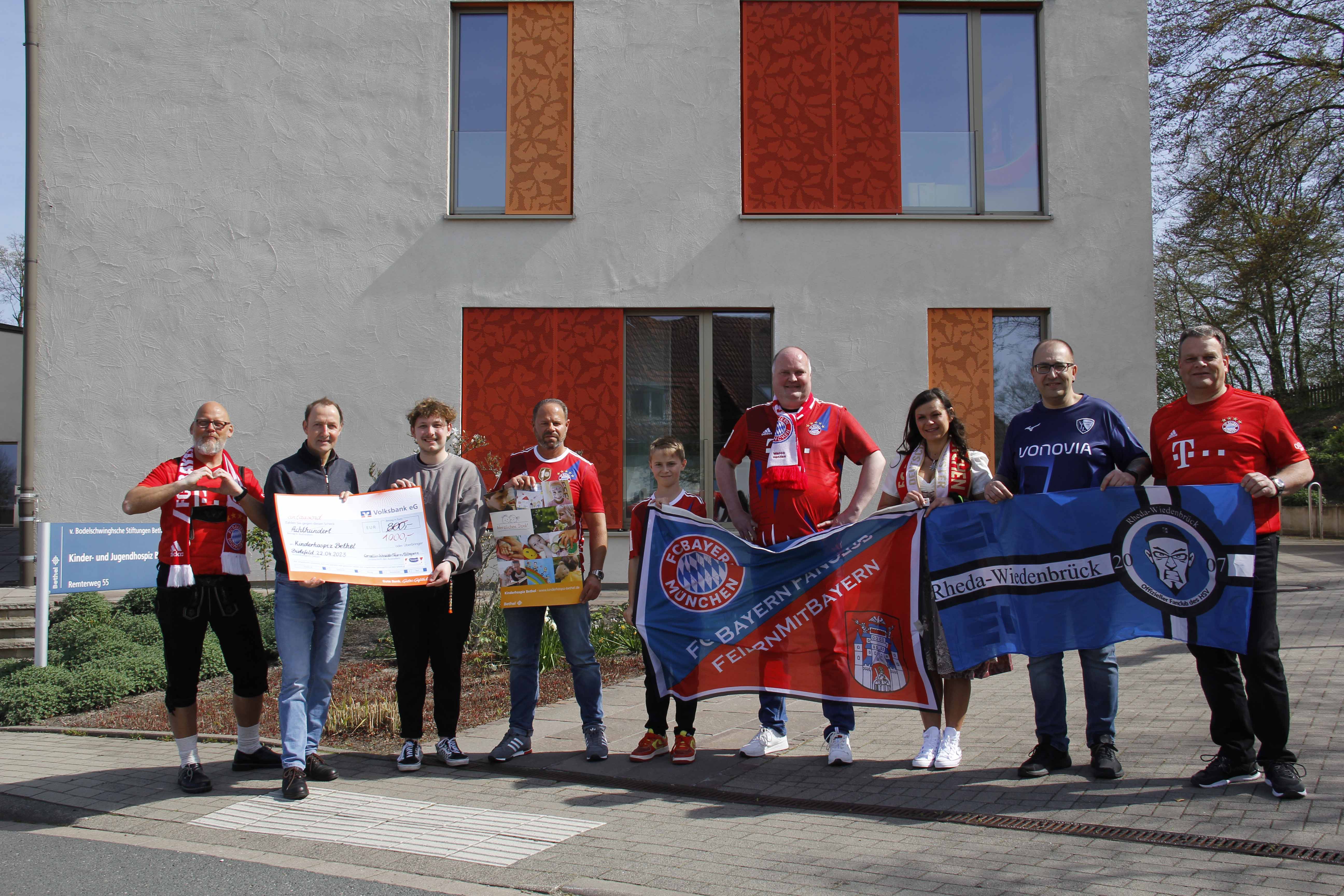 Oelde/Bethel. „Wir sind davon überzeugt, dass unsere Spende bei Ihnen hervorragend angelegt ist“, zeigte sich Elmar Pierenkemper, Vorstandsmitglied des Stromberger Fußball-Fanclubs feiernmitbayern, kürzlich nach der Vorstellung der Arbeit des Kinder- und Jugendhospiz‘ in Bethel beeindruckt. Reinhard Elbracht, Ansprechpartner v. Bodelschwinghsche Stiftungen Bethel, sowie Christian Penner, Mitglied des pädagogischen Teams des Hospiz‘, hatten Vorstand und Mitglieder des Fanclubs zuvor über das Gelände geführt und von der einzigartigen Atmosphäre und Arbeit des Hauses berichtet. Bis zu 10 Kinder und junge Menschen im Alter von 0 bis 27 Jahren mit einer lebensverkürzenden Erkrankung können ab Diagnosestellung mit ihren Familien in der Einrichtung aufgenommen und einfühlsam betreut werden. Während die Erkrankten medizinisch bestens versorgt werden und je nach Krankheitsstadium noch Kunst-, Musik- oder Reittherapien nutzen können, können Eltern in idyllischer Landschaft in Ruhe ausspannen und Geschwister auf dem Gelände nach Herzenslust toben oder mit dem pädagogisch geschulten Personal spielen. „Die Krankenkassen übernehmen nur die anfallenden Kosten für das erkrankte Kind“, berichtete Reinhard Elbracht. Die Unterbringung, Betreuung und Freizeitgestaltung für den Rest der Familie müsse gänzlich aus Spenden finanziert werden. Selbst die Einrichtung als solches, die im letzten Jahr ihr 10-jähriges Jubiläum feierte, ist nur aus Spendengeldern errichtet worden. Der Fanclub überbrachte einen Spendenscheck in Höhe von 1.000 Euro. Der ursprüngliche Betrag war kurzfristig noch um 200 Euro aufgestockt werden, nachdem der Stromberger Malermeister Thomas Gerke spontan einen Beitrag geleistet hatte. Dass es sich dabei um einen Fan des Hamburger SV handelt, spielt keine Rolle, da das gelebte Motto von feiernmitbayern „In den Farben getrennt, in der Sache vereint“ über jede Vereinsrivalität steht. Seit 25 Jahren organisieren der Stromberger Marco Hendan und Team Busfahrten zu attraktiven Bundesligaspielen, für die die Vereine VfL Wolfsburg, Bayer 04 Leverkusen und FC Bayern München größere Kontingente zur Verfügung stellen. Aus einem großzügigen Pauschalbetrag für Fahrt, Verpflegung und Eintrittskarte, aus den Erlösen einer Tombola im Bus sowie aus Beiträgen anderer Fanclubs generieren die Fußballfans Spenden, die sie einmal im Jahr an drei ausgewählte Einrichtungen überreichen. Über Vorstandsmitglied Ralf Büscher entstand der Kontakt nach Bethel. Reinhard Elbracht bedankte sich im Namen der betroffenen Familien und des Betreuungsteams: „Ich finde es beeindruckend, dass Sie Ihre Leidenschaft für den Fußball ausleben und dabei noch an andere denken. Wir können die Erkrankungen nicht verhindern, aber den Familien ihre Lebenssituation zeitweise etwas erleichtern.“ Eine bunte und ansprechende Gestaltung des Außengeländes und der Inneneinrichtung leisten ebenfalls ihren Beitrag. „Bei aller Belastung und Trauer erleben wir an diesem Ort auch viel Lebensfreude und tiefe Dankbarkeit“, berichtet Christian Penner, der wie viele andere Mitarbeitende und ehrenamtlich Tätige seiner herausfordernden Arbeit „mit professioneller Nähe“ nachgeht. Wer sich über die Arbeit des Kinder- und Jugendhospiz informieren will, hat am Tag der offenen Tür am 6. Mai von 11 bis 17 Uhr Gelegenheit dazu. Weitere Informationen: www.kinderhospiz-bethel.de